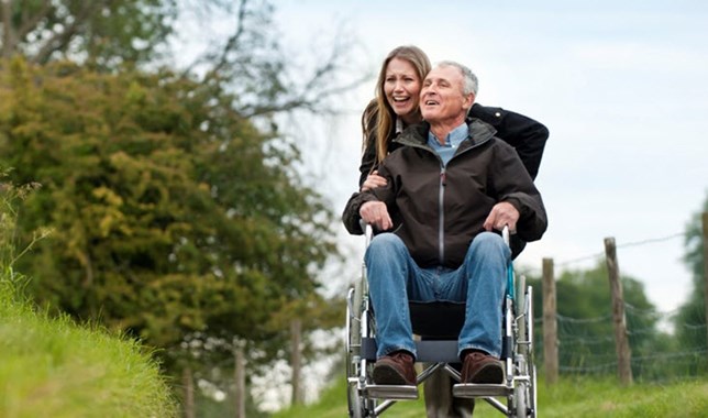 Caregiver and loved one in wheelchair happily living in the moment as they go for a walk